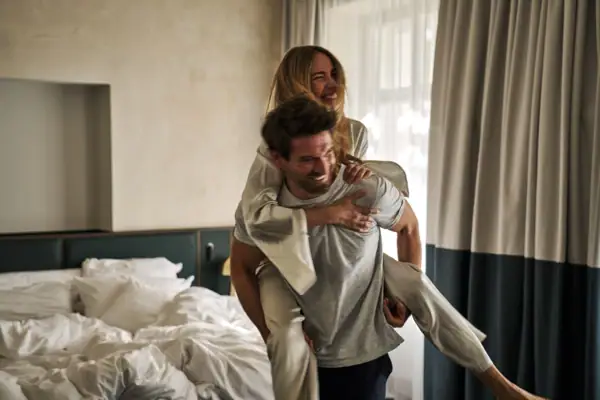 Eine Frau trägt einen Mann im Bett.