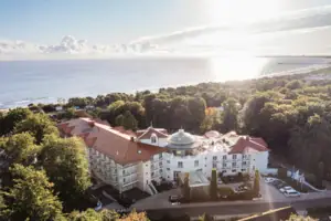A-ROSA Heringsdorf Großes Gebäude mit Bäumen und einem Gewässer im Vordergrund.