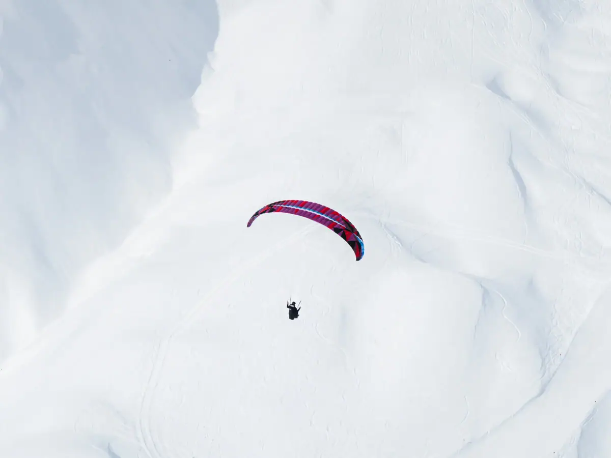 Eine Person beim Fallschirmspringen im Schnee.