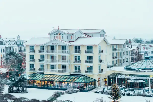 A-ROSA Ostseehotel Kühlungsborn Ein Gebäude im Schnee mit Bäumen im Hintergrund.