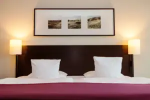 Zimmer Ein Bett mit zwei Kissen und einem Bild an der Wand.