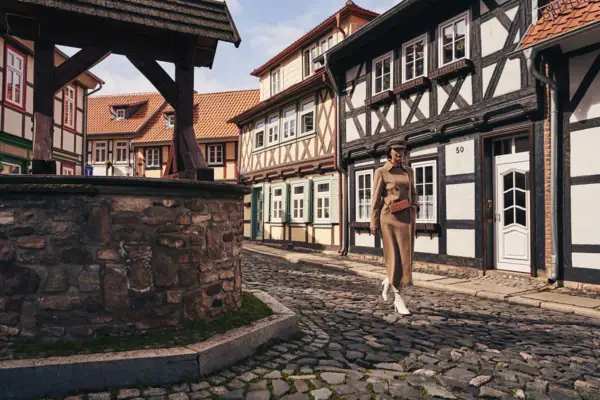 Fachwerkstadt Eine Frau geht auf einer Kopfsteinpflasterstraße, im Hintergrund sind Gebäude zu sehen.