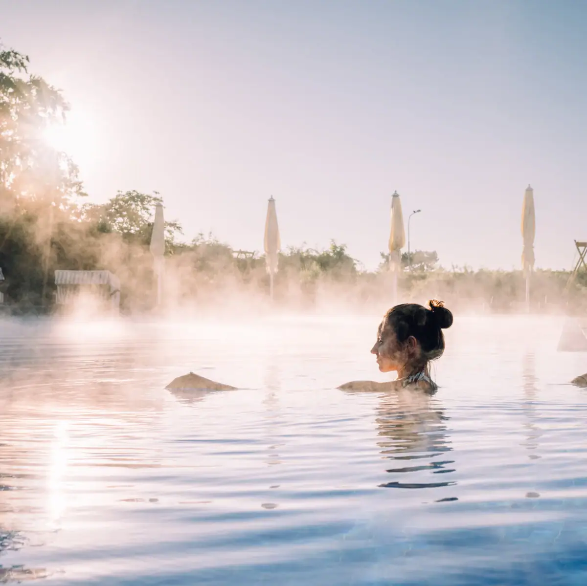 Außenpool Travemünde Eine Frau im dampfenden Außenpool bei Sonnenaufgang..