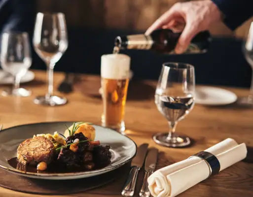 Spezialitätenrestaurant Carnozet Eine Person schenkt ein Getränk in ein Weinglas ein.