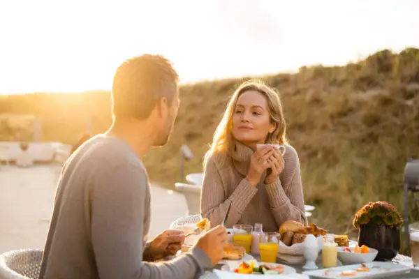 Frühstück zwischen den Dünen Ein Mann und eine Frau sitzen an einem Tisch mit Essen.