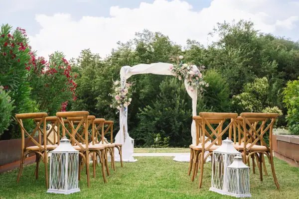 Traubogen im Grünen im A-ROSA Gardasee Hochzeitsbogen mit Blumenarrangement und Stühlen im Garten für die Trauung.