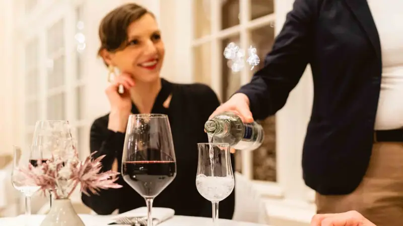 Eine Frau schenkt Wein in ein Glas ein.