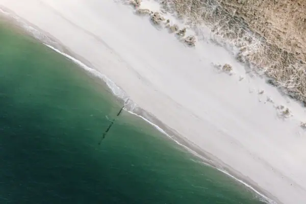 Hörnum-Odde Ein schöner Strand auf Sylt mit Sand und Wasser aus der Vogelperspektive.