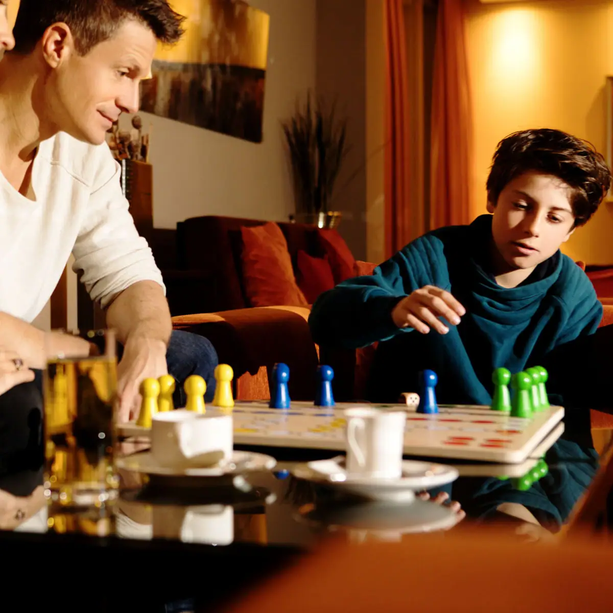 Eine Gruppe von Menschen sitzt an einem Tisch und spielt ein Brettspiel.