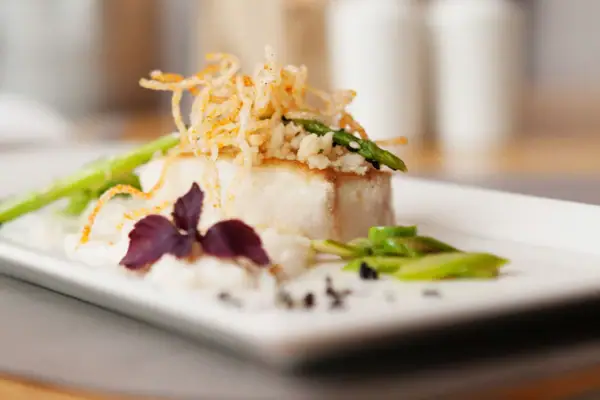 Tellergericht A-ROSA Sylt Ein Teller mit Essen auf einem Tisch.