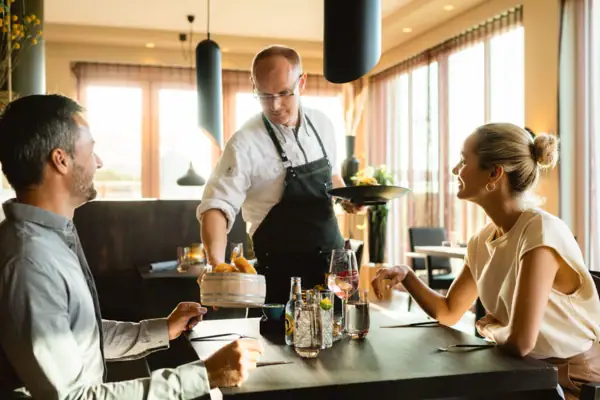 Dinner Ein Mann serviert Essen an ein Paar.