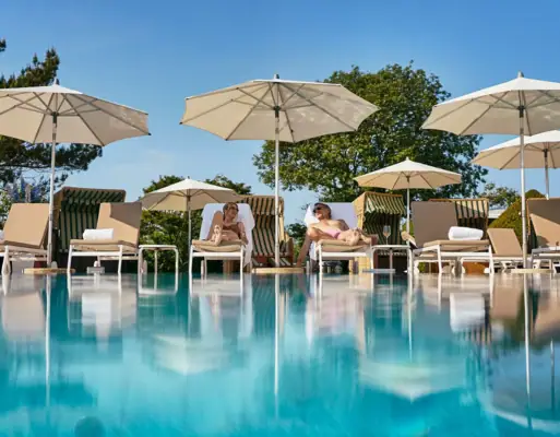 Eine Gruppe von Menschen sitzt in Stühlen am Pool.