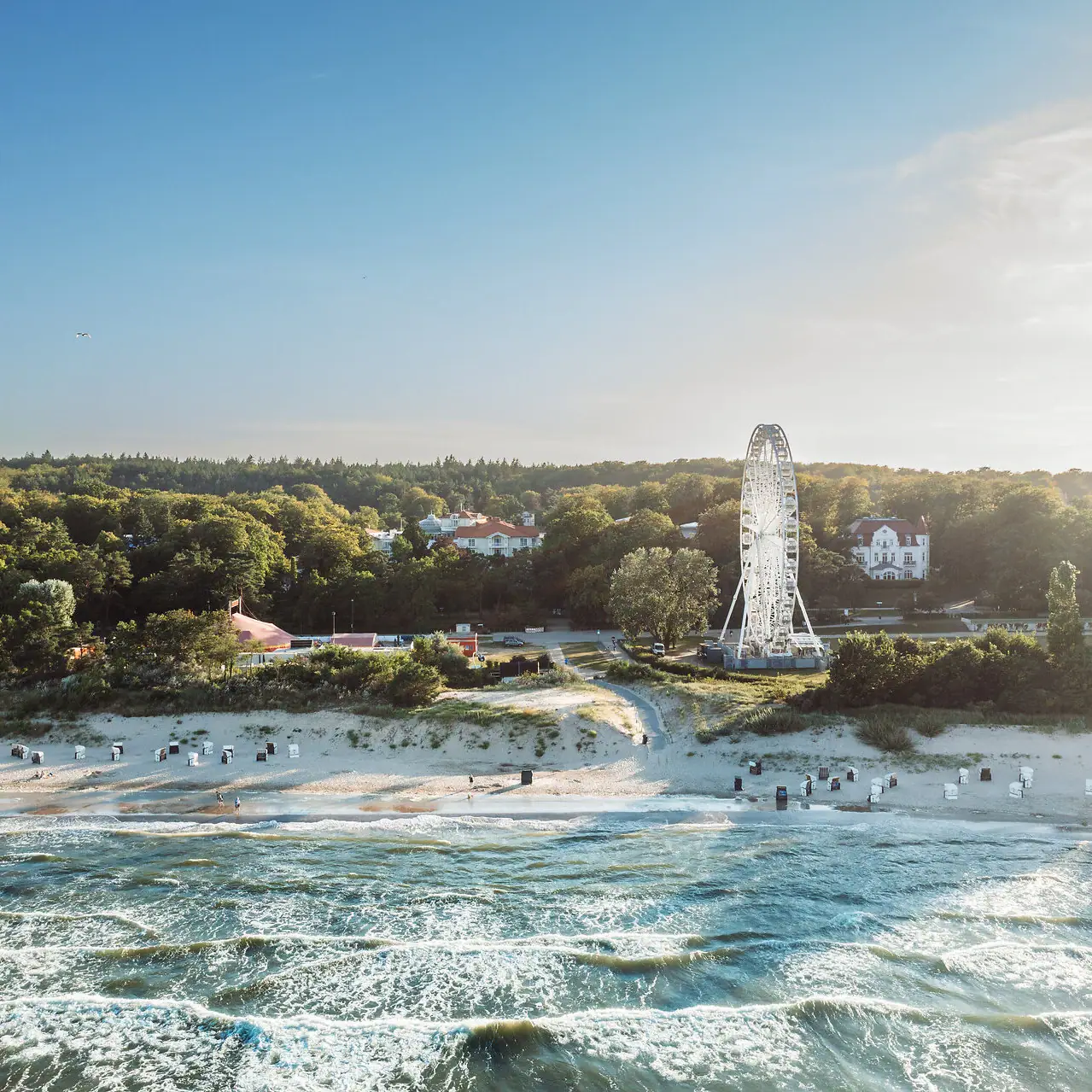 Strand mit Riesenrad und Bäumen im Hintergrund.