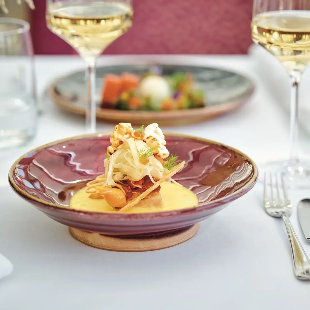 Ein Teller mit Essen auf einem Tisch, daneben ein Weinglas.