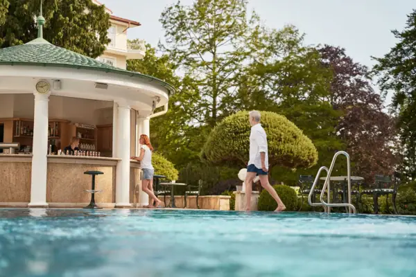Ein Mann und eine Frau gehen an einem Pool entlang.