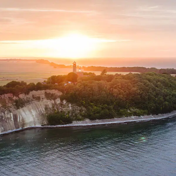 Ein Leuchtturm auf einem Hügel am Wasser.