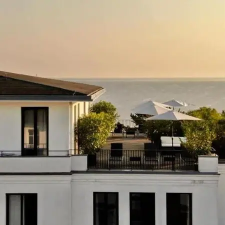 Ein Gebäude mit Balkon und Bäumen am Rand.