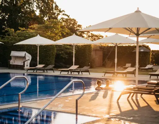 Außenpool Travemünde Ein Pool mit Sonnenschirmen und Liegestühlen.