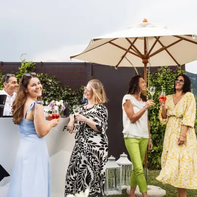 Eine Gruppe von Menschen steht im Freien mit Getränken.