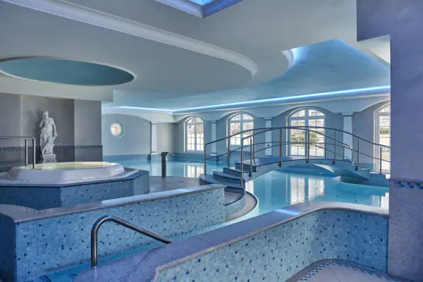 Ein großes Hallenbad mit Whirlpool und Treppe.