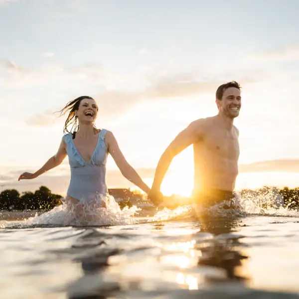 Ein Mann und eine Frau halten sich im Wasser an den Händen.