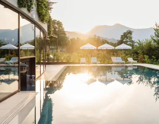 Außenpool im A-ROSA Gardasee Ein Pool mit Liegestühlen und Sonnenschirmen vor einem Haus.