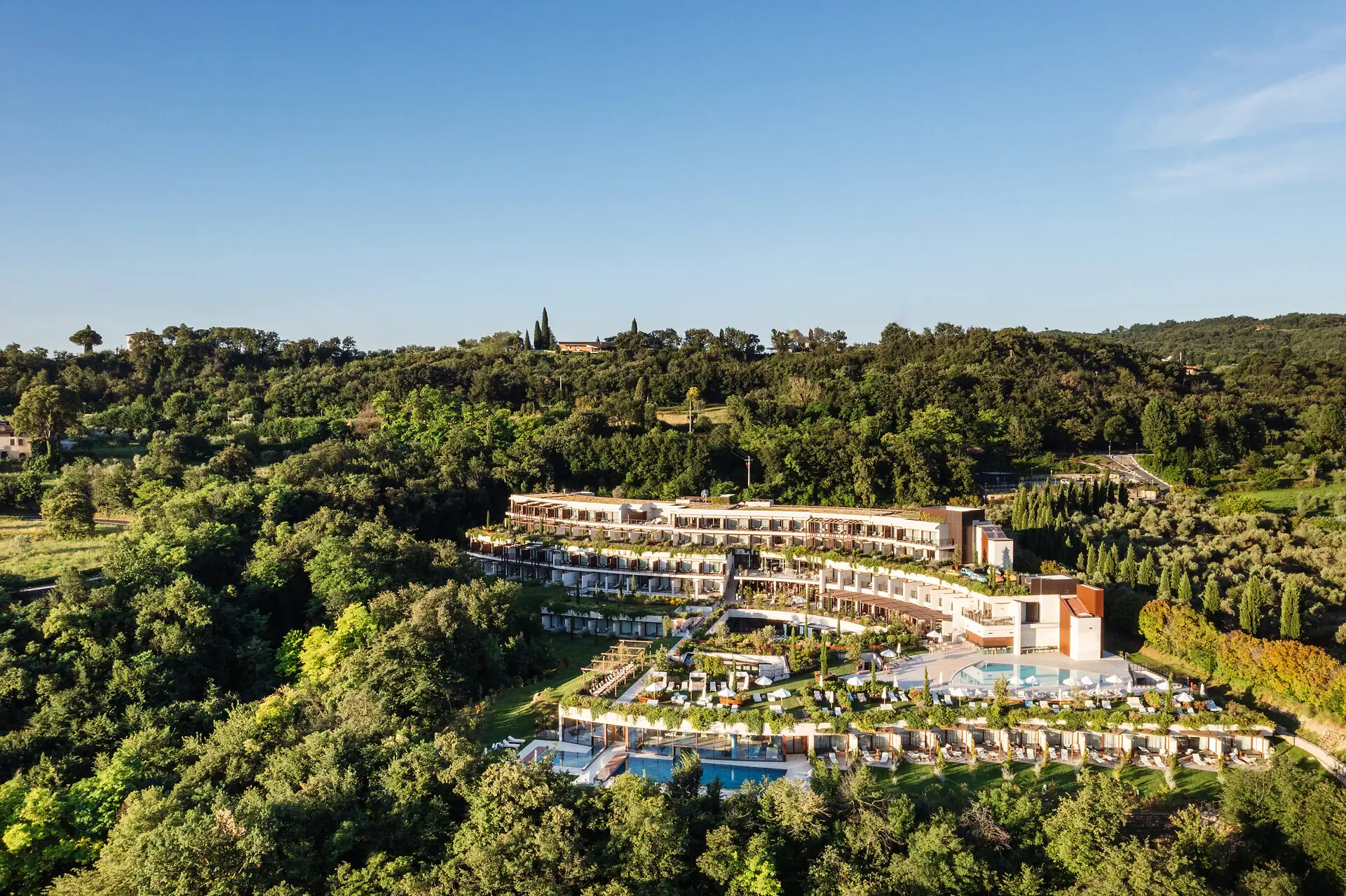 A-ROSA Hotel am Gardasee Ein Gebäude mit einem Pool, umgeben von Bäumen.