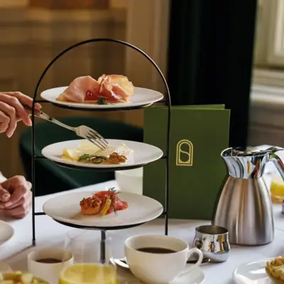 Frühstück im Grand Hotel Eine Etagere mit Lebensmitteln, Teekanne und Menükarte