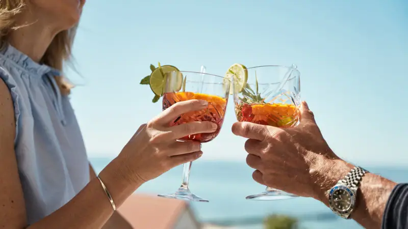 Ein Paar Hände hält Gläser mit Getränken.