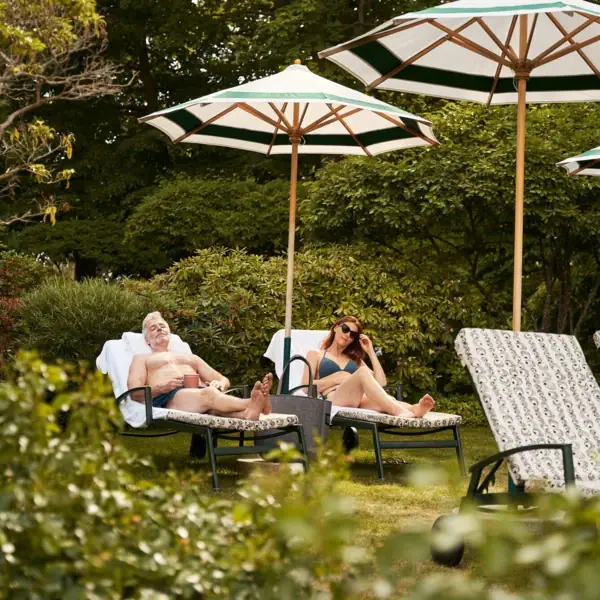 Ein Mann und eine Frau sitzen auf Liegestühlen unter Sonnenschirmen.