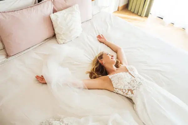 Zimmer im A-ROSA Gardasee Eine Frau liegt auf einem Bett in ihrem Hochzeitskleid.