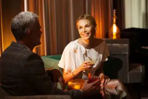 Negroni Lounge Eine Frau hält ein Getränk, während ein Mann auf einem Sofa sitzt.