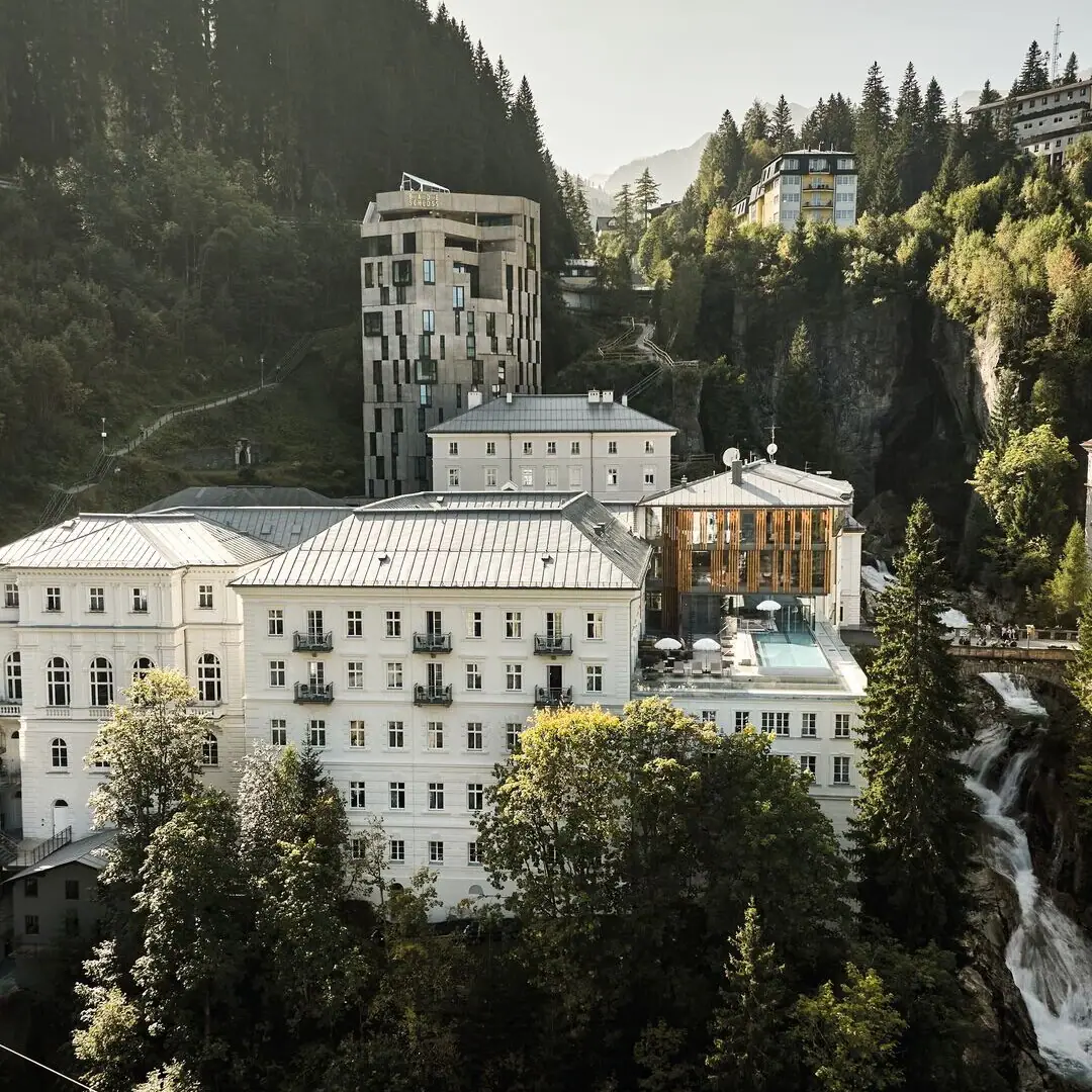 Eine Gruppe von Gebäuden mit Bäumen und Bergen im Hintergrund.