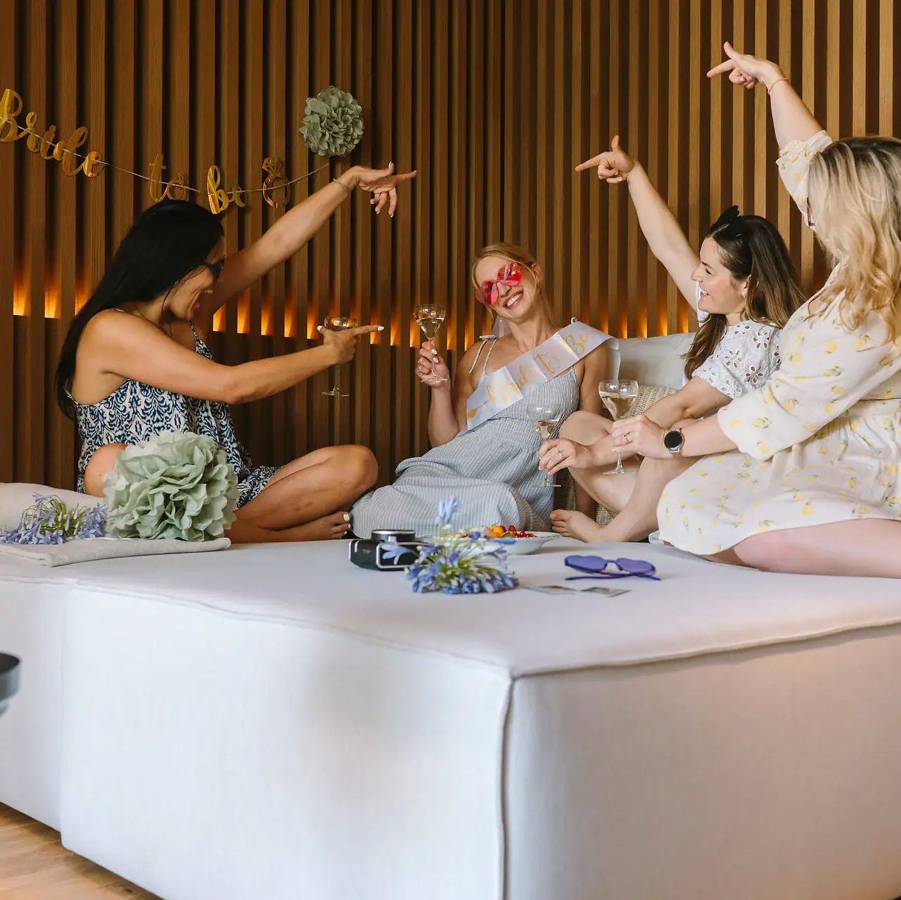 Junggesellenabschied am Gardasee Eine Gruppe von Frauen sitzt mit Getränken auf einem Bett.