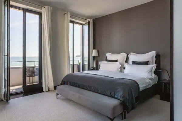 Ein Schlafzimmer mit einem großen Fenster, das auf das Meer blickt.