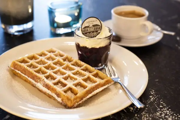 Waffeln mit Puderzucker Waffel und Tasse Kaffee auf einem Tisch