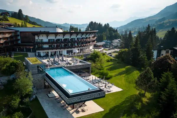 Ein Außenpool in einem Hotel, umgeben von Bäumen und einem klaren Himmel.