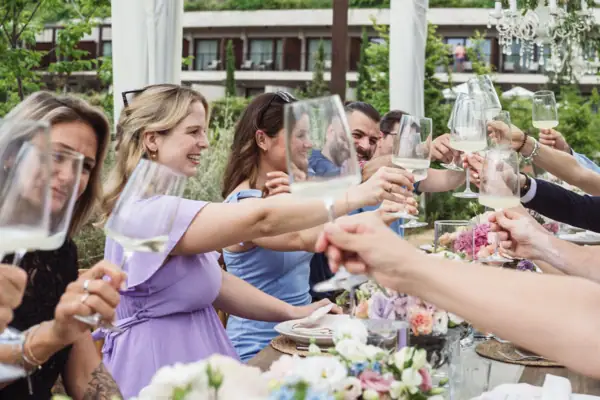 Team beim gemeinsamen Anstoßen im A-ROSA Gardasee Gruppe von Menschen stößt bei einem festlich gedeckten Tisch im Freien an