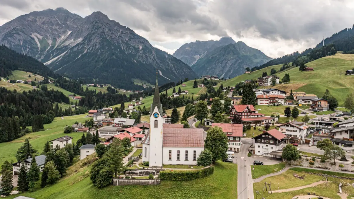 Eine Kirche in einem Tal mit Bergen im Hintergrund.