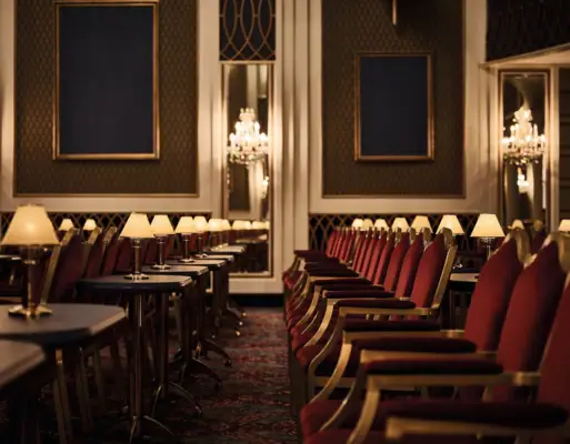 Saal Kurhaus Binz Ein relativ dunkler Raum mit roten Stühlen und Lampen.