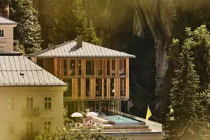 A-ROSA Bad Gastein Gebäude mit Pool in der Mitte, umgeben von Bäumen und Pflanzen.