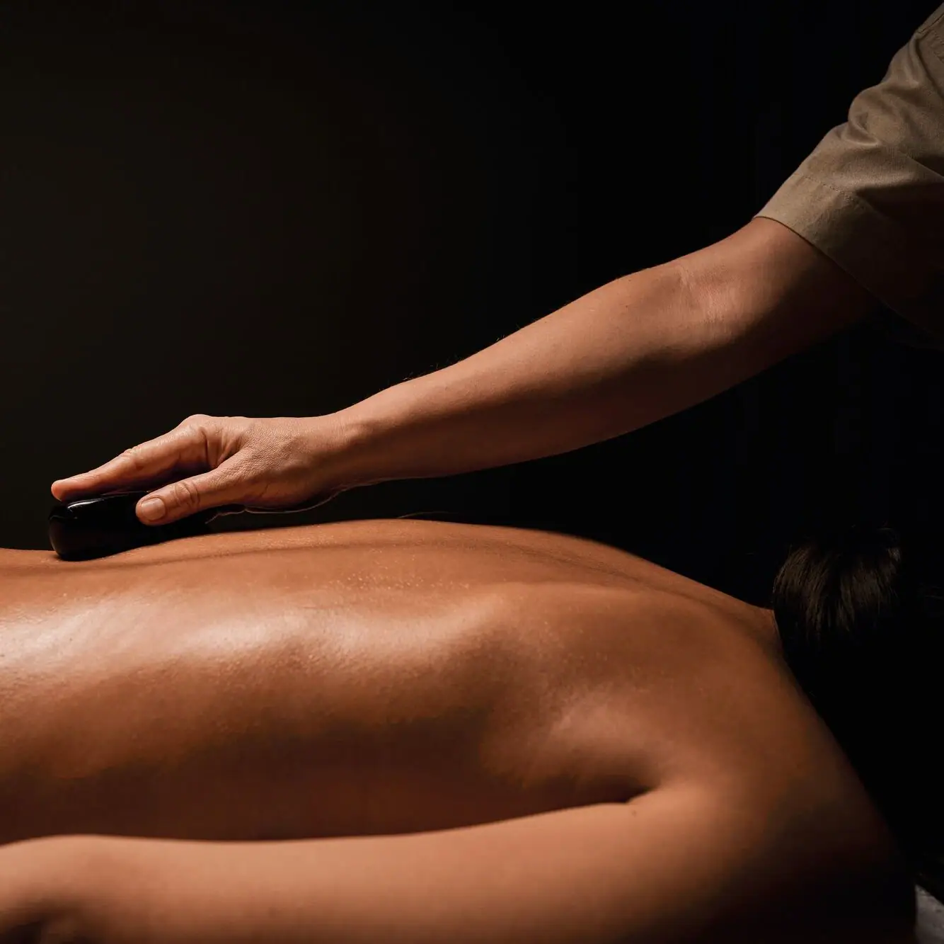 Wellnessmomente für tiefe Entspannung Nahaufnahme eines Rückens welcher mit Hot Stones behandelt wird