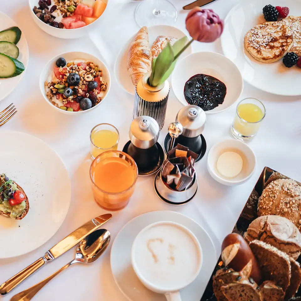 Frühstücksauswahl im Restaurant Ein gedeckter Frühstückstisch mit Brotkorb, Pancakes, Saft und Cerealienauswahl