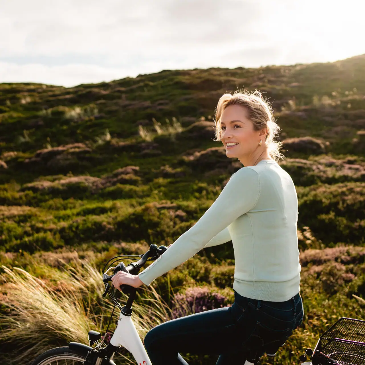 Eine Frau fährt Fahrrad in einem grasbewachsenen Gebiet.