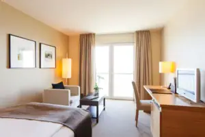 Einzelzimmer Wohnraum Ein Zimmer mit einem Bett, einem Schreibtisch und Stühlen.