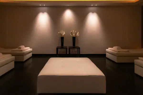 Ein Zimmer mit einem weißen Bett und zwei schwarzen Stühlen.