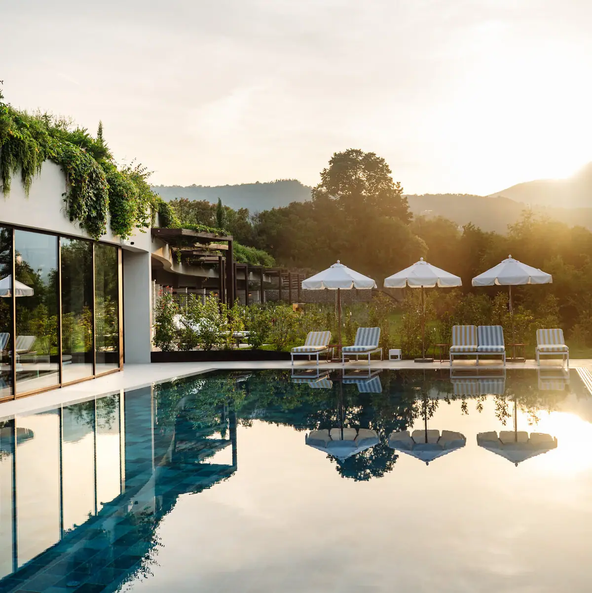 Außenpool am Gardasee Ein Pool mit Liegestühlen und Sonnenschirmen vor einem Gebäude.