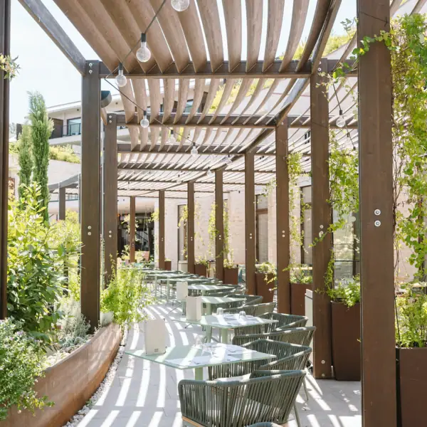 Außenbereich vom Restaurant des A-ROSA Gardasee Überdachte Terrasse mit Tischen und Stühlen.