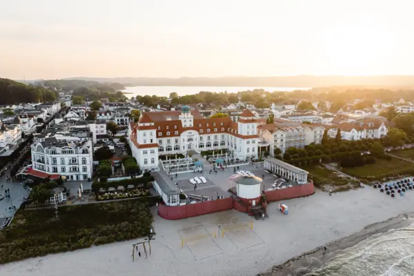 Kurhaus Binz Strand mit Gebäuden und einem Gewässer im Hintergrund.