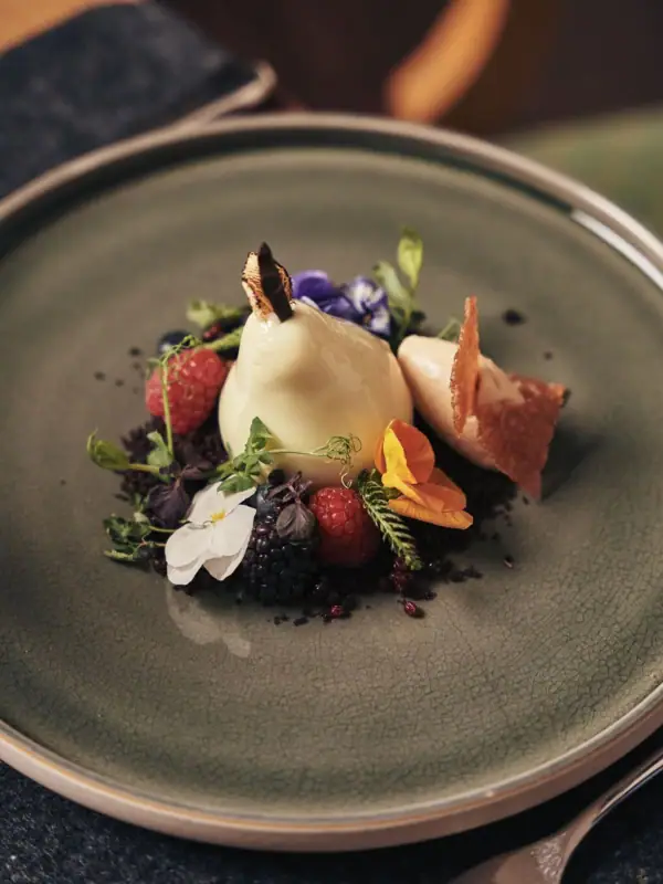 A-RSOSA Gericht Ein Teller mit kunstvoll angerichteten Früchten und Blumen.